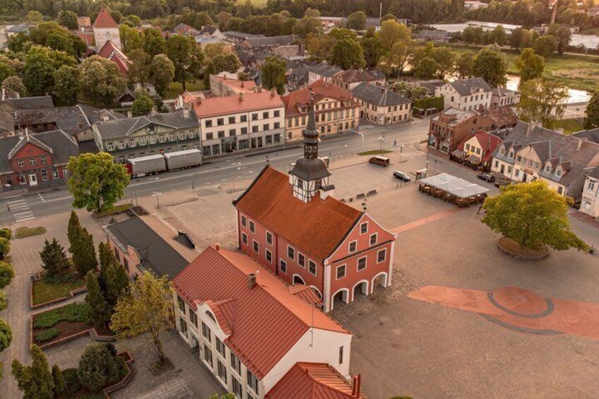 An aerial view of a town square with historic buildings, a prominent church, and a large open area. 3