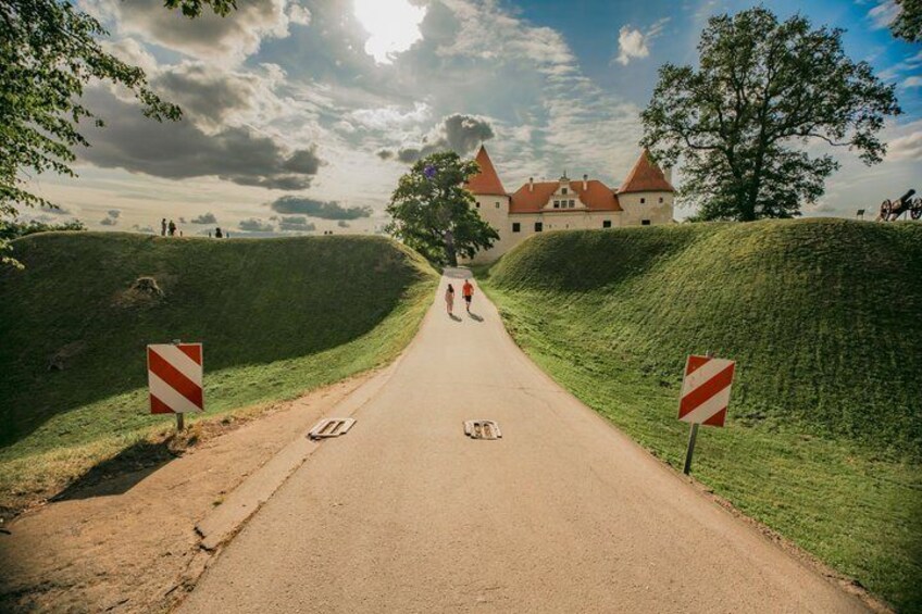 A road leading to a castle with two red and white striped signs on either side. 2