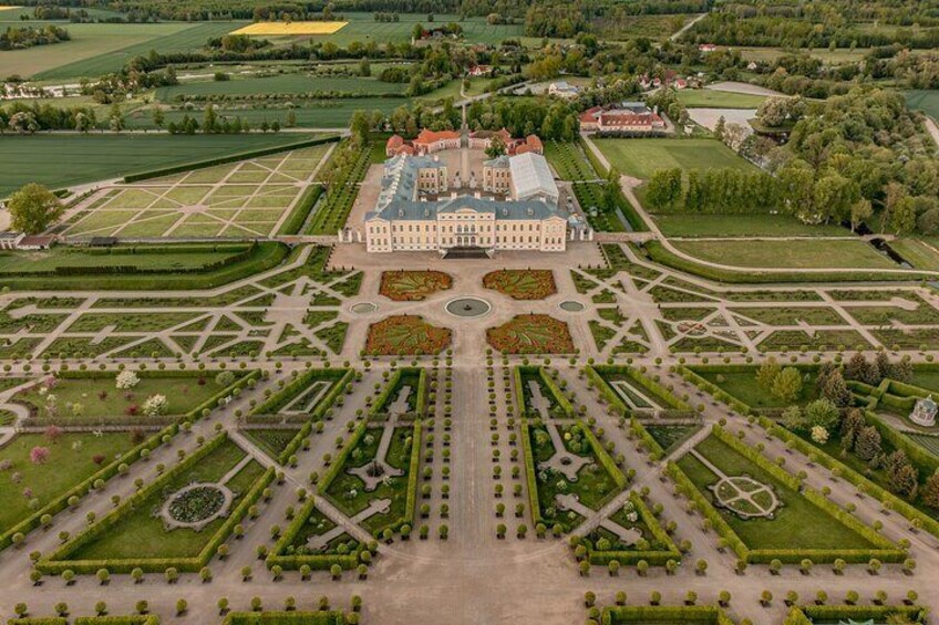 A grand palace with symmetrical gardens and a large central lawn. 1