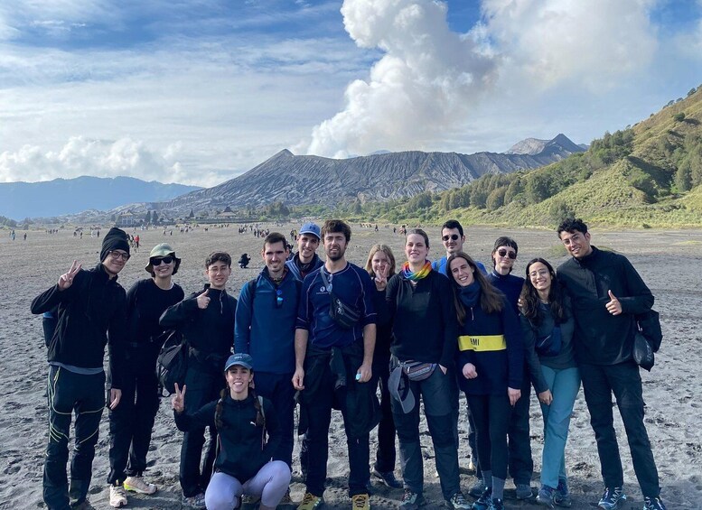 A group of people on a beach with mountains in the background. 2
