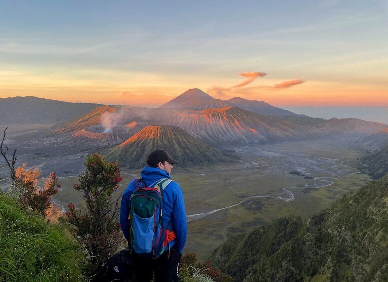 A hiker overlooking a volcanic landscape at sunset. 1