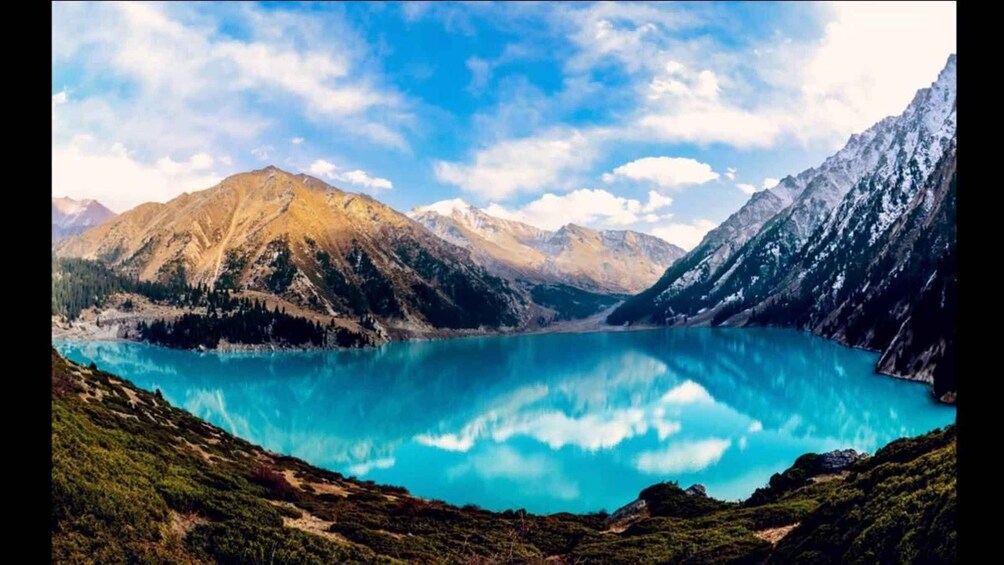A mountain lake with clear turquoise water, surrounded by rugged mountains and lush greenery. 2