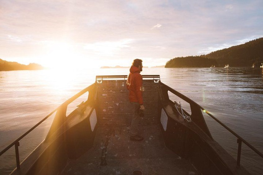 A person standing on a boat deck during sunset. 2
