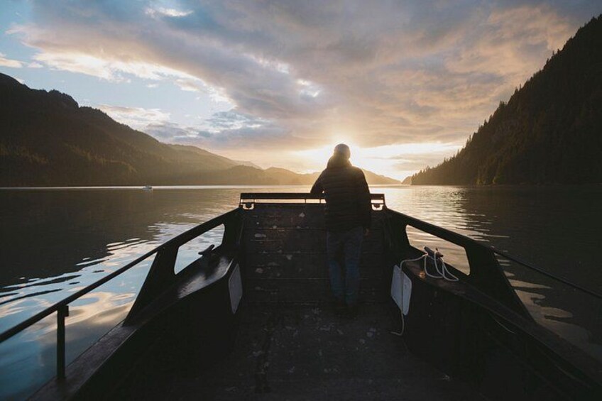 A person on a boat at sunset with mountains in the background. 1