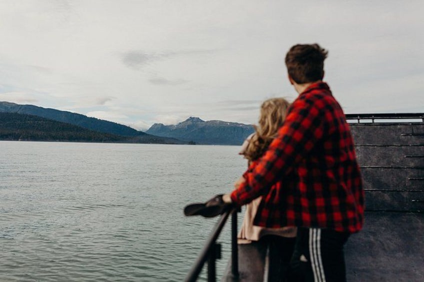 A couple standing by a lake with mountains in the background. 4