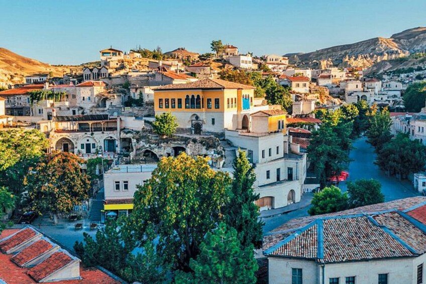 A hillside town with terracotta-roofed buildings, a prominent yellow building with blue accents, and a river running through the center. 5