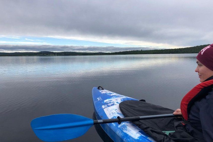 A person in a kayak on a calm lake with a cloudy sky. 1