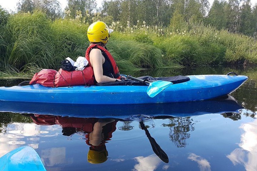 A person in a blue kayak with a yellow helmet, red life jacket, and a red bag. 3