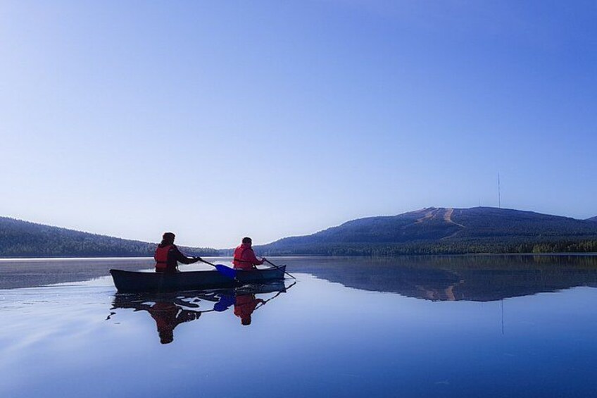 Two people in a boat on a calm lake with mountains in the background. 5