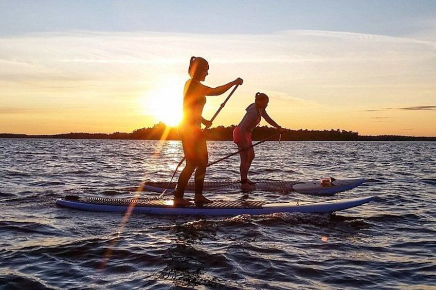 Two people paddleboarding on a body of water during sunset. 4