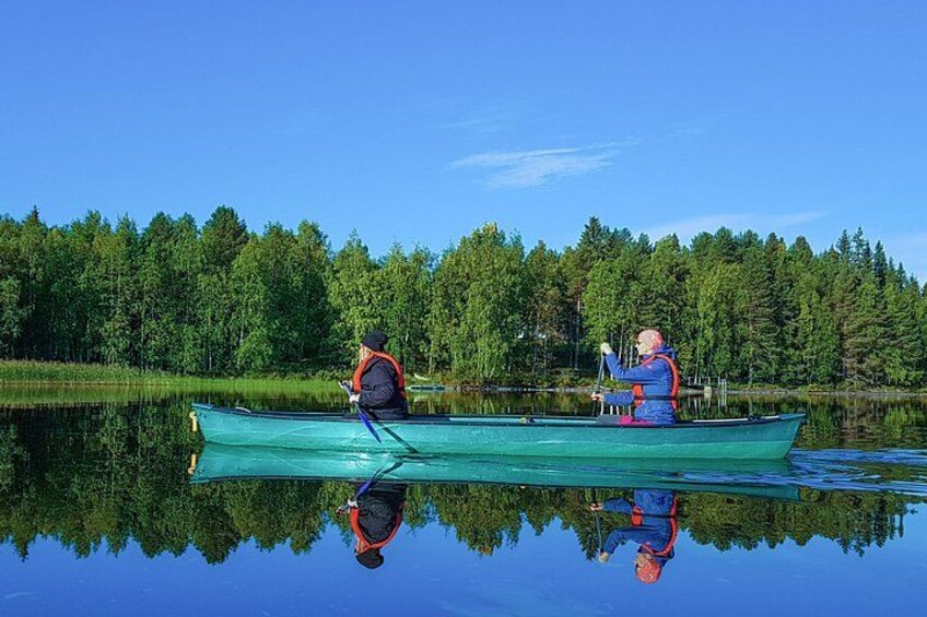 Two people canoeing on a calm lake with dense forest in the background. 2