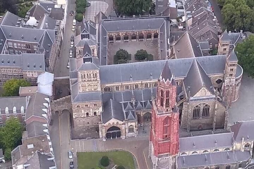 An aerial view of a historic town with a prominent church featuring a tall spire and a large courtyard. 2