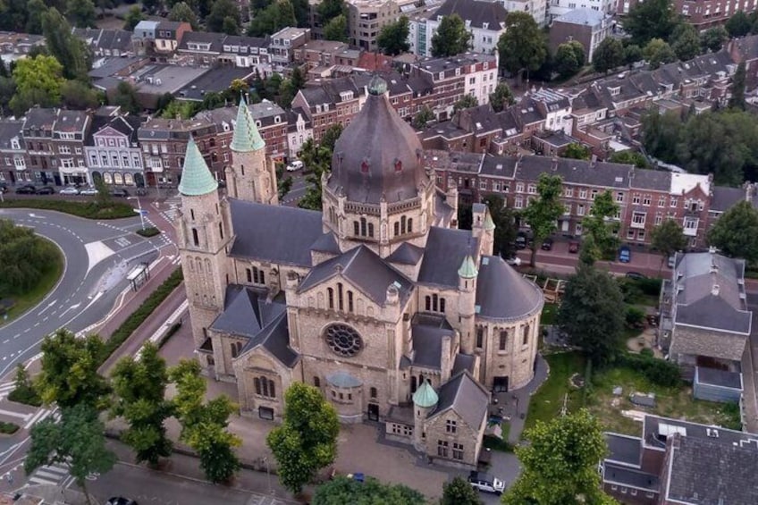 A historic church with multiple spires and a large central dome, surrounded by residential buildings and a roundabout. 1