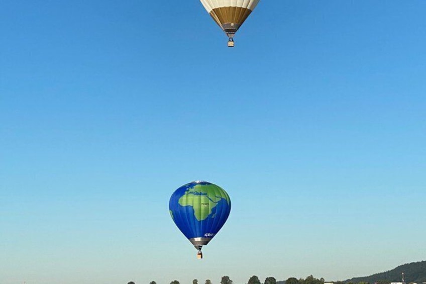 A hot air balloon with a globe design flying above a landscape. 3