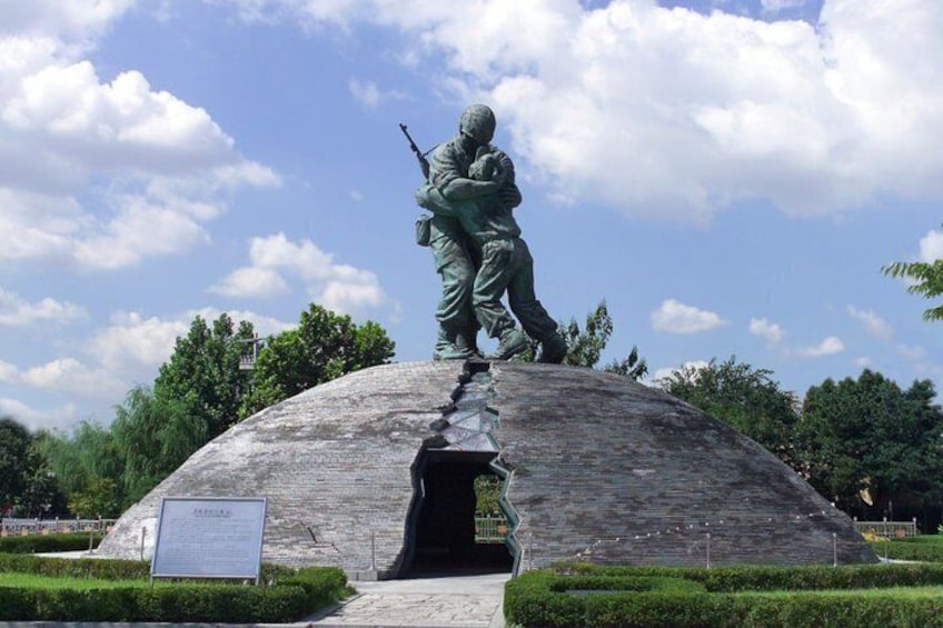 Una estatua de soldados en un monumento de forma abovedada con un letrero al frente. 5