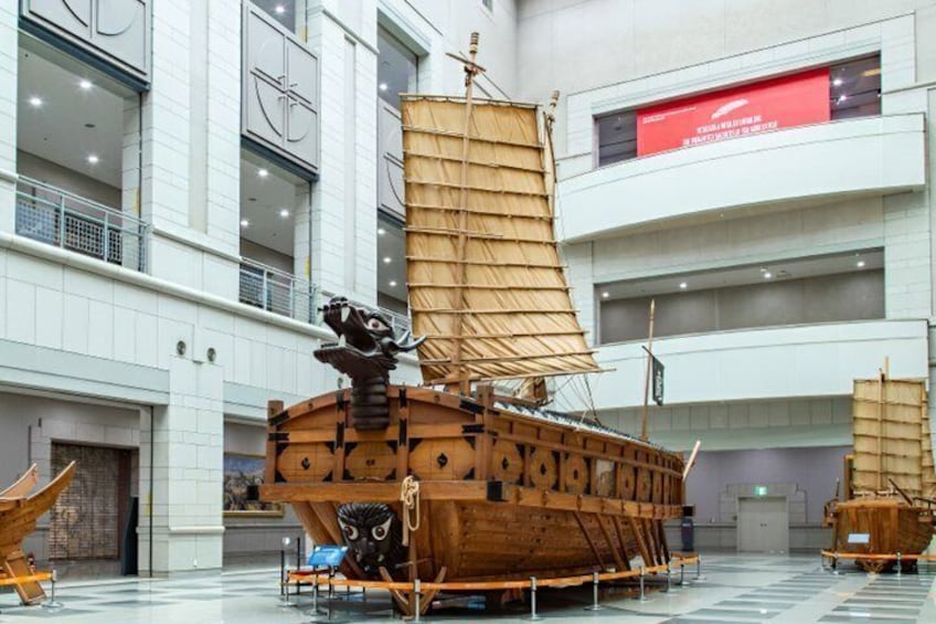 Un modelo grande de barco de madera exhibido en un espacio interior con techo alto y arquitectura moderna. 4