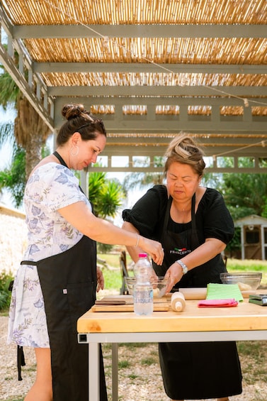Two people preparing food outdoors under a bamboo roof. 4