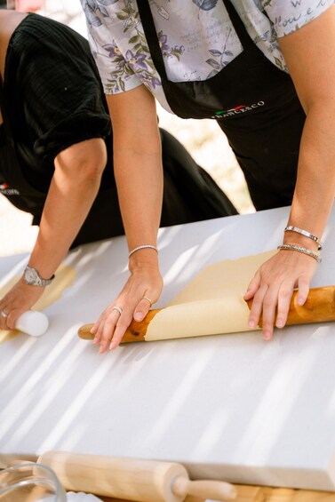 A person rolling dough on a white surface with a rolling pin. 5