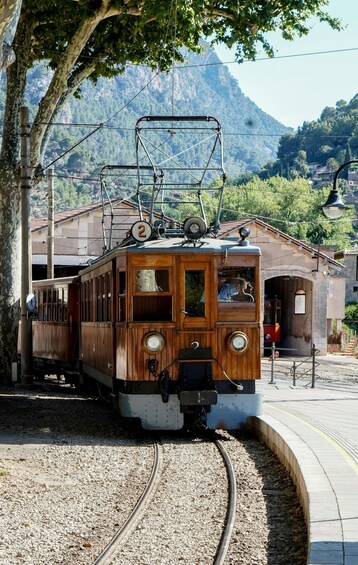 A vintage tram at a station with a mountainous backdrop. 5