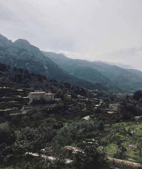 A mountainous landscape with scattered buildings and dense vegetation. 1