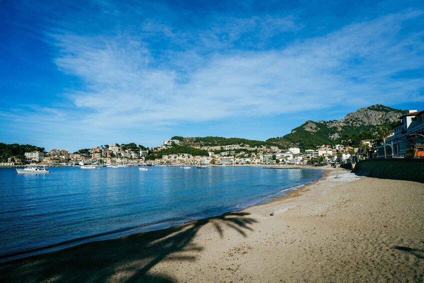 A coastal town with buildings along the shore, a clear blue sky, and a mountain in the background. 4