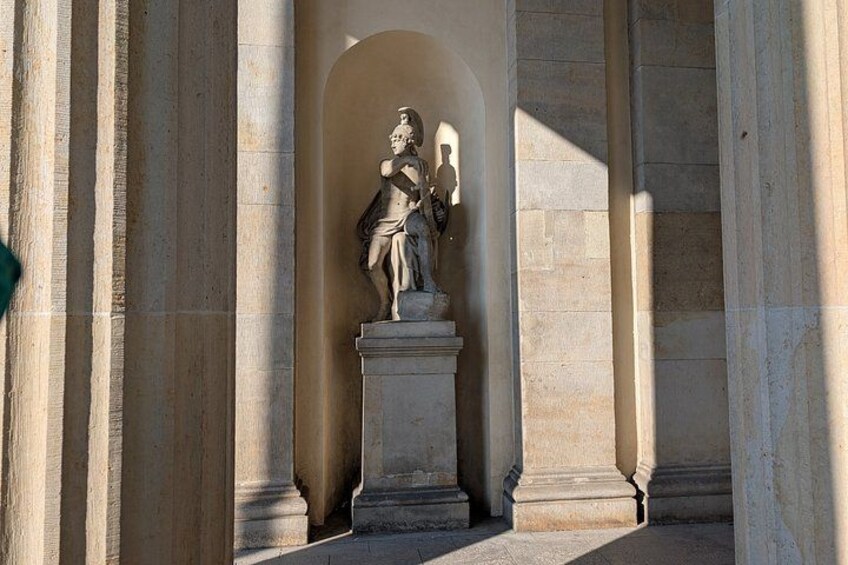 En klassisk statue i en buet alcove, omgivet af stensøjler. 2