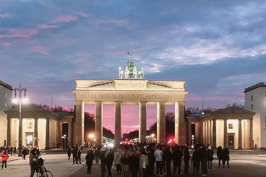 Het Brandenburger Tor met kolommen en een beeldhouw op de top, omringd door mensen en gebouwen. 1