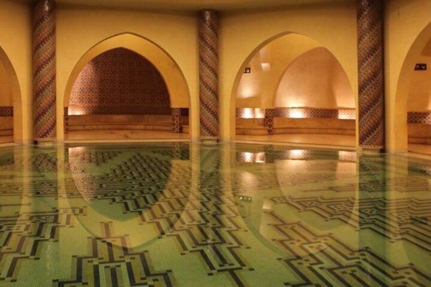 Ein großes Hallenbad mit geometrischen Fliesenmustern, gewölbten Decken und Wandverzierungen. 1