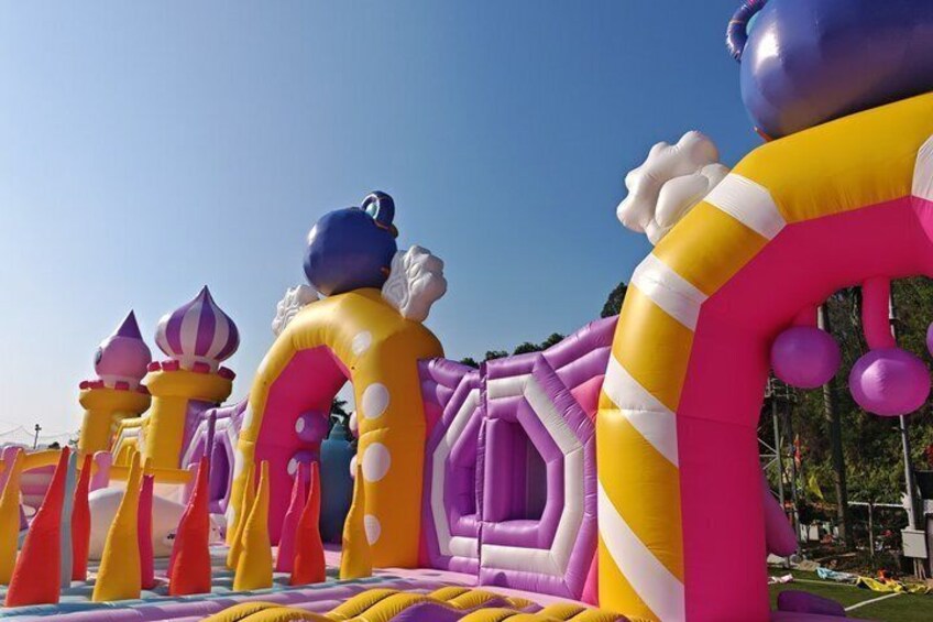A colorful inflatable castle with various structures including a castle, a dragon, and a princess. 3