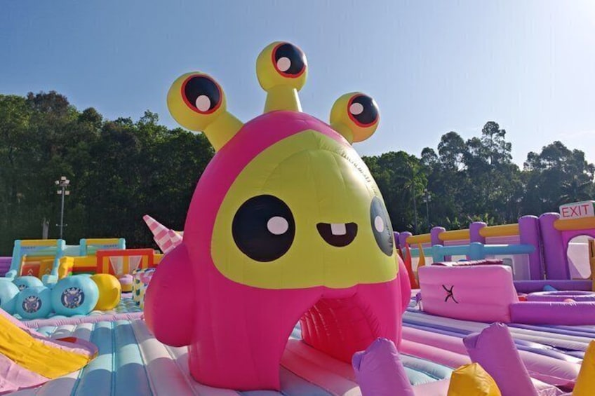 A colorful inflatable structure with a pink and yellow design, surrounded by various inflatable play areas. 2