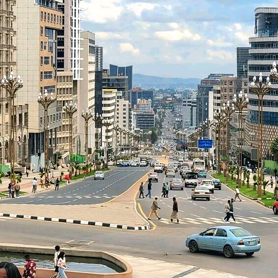 A city street with buildings, cars, and pedestrians. 1