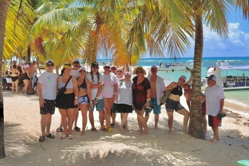 A group of people on a sandy beach with palm trees and a clear blue sky. 3