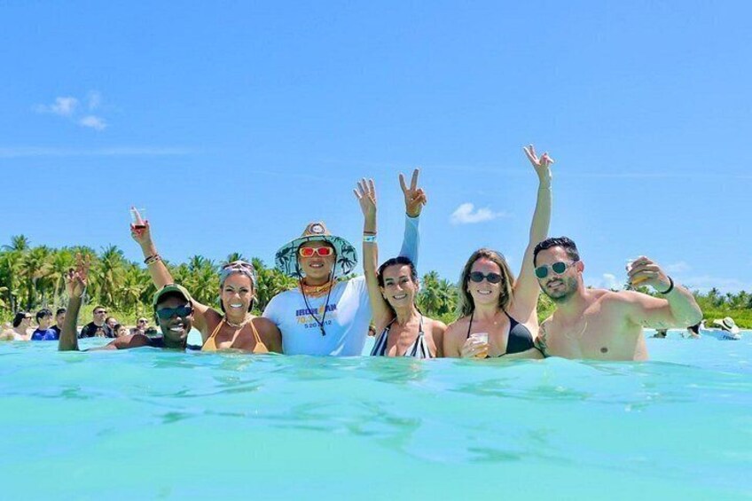 A group of people in a clear blue pool with palm trees in the background. 2