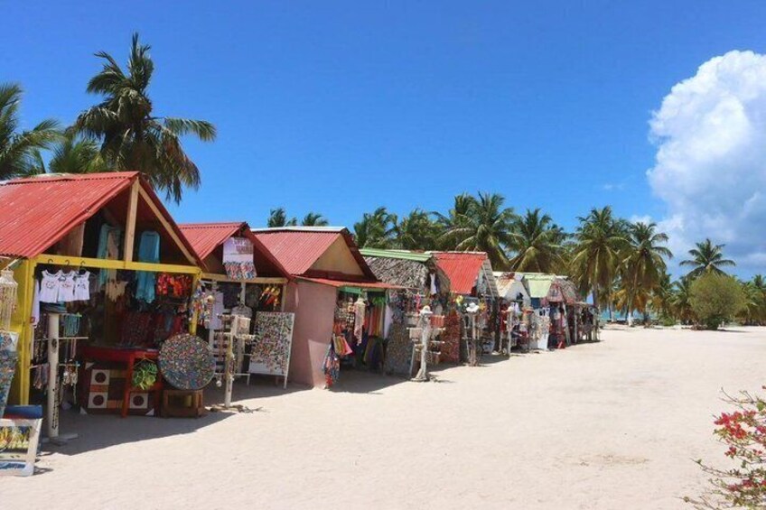 A row of colorful beachside shops with red roofs and palm trees in the background. 5