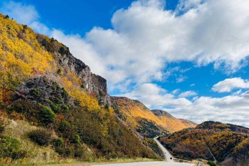 A winding road through a mountainous landscape with autumn foliage. 4