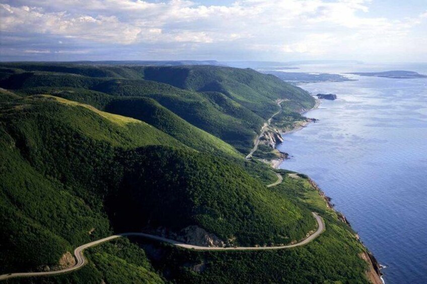 A winding coastal road through a forested landscape with a view of the ocean. 2