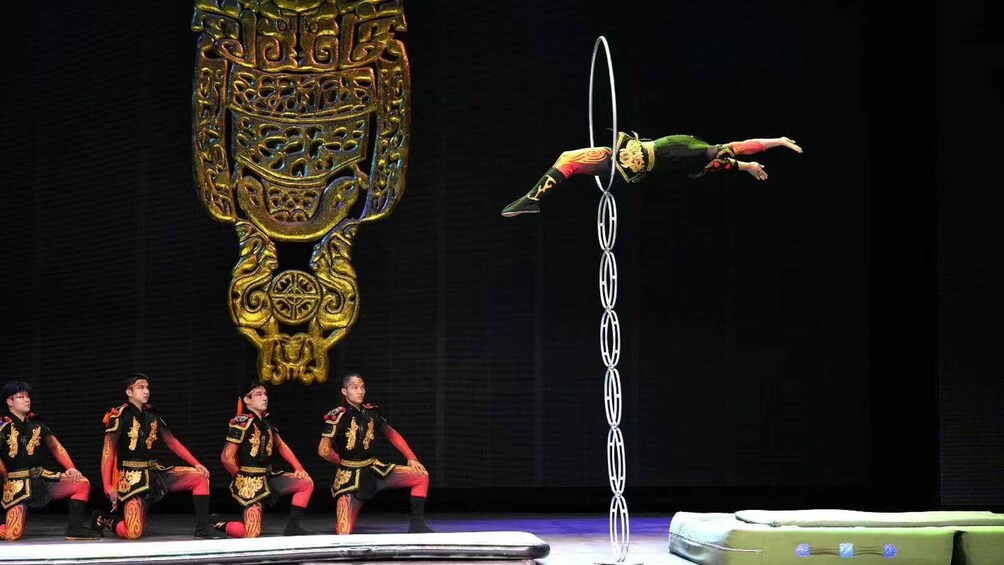 A performer on a hoop, surrounded by a group in matching uniforms. 1