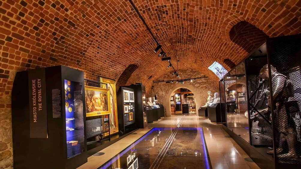 An indoor museum with brick walls, glass display cases, and a central reflective floor. 3