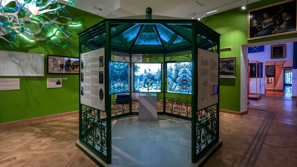 A green gazebo with informational panels and a view of trees through the windows. 4