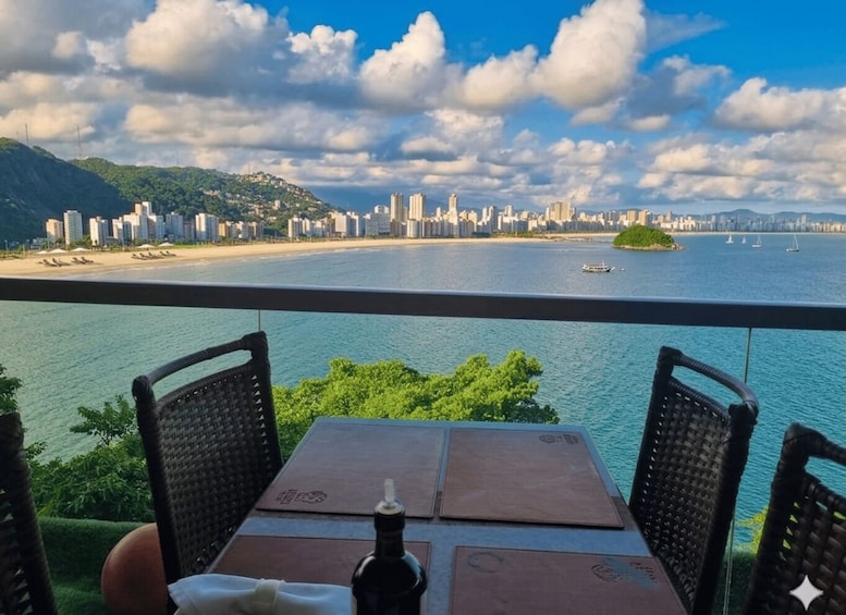 A table with chairs overlooking a coastal cityscape with a beach and mountains in the background. 5