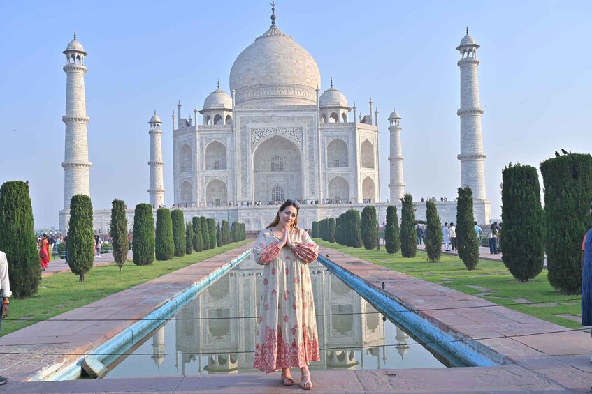 Une personne se tient devant le Taj Mahal, avec ses quatre minarets et son dôme central. 4