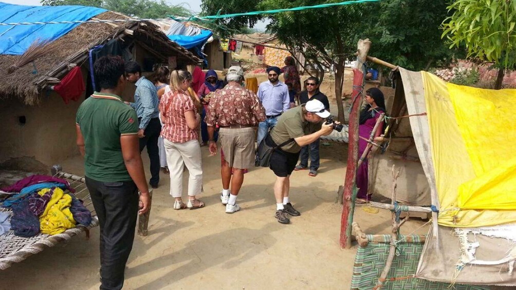 Un groupe de personnes se trouve dans un environnement rural, avec des huttes aux toits de chaume et des abris de fortune. 5