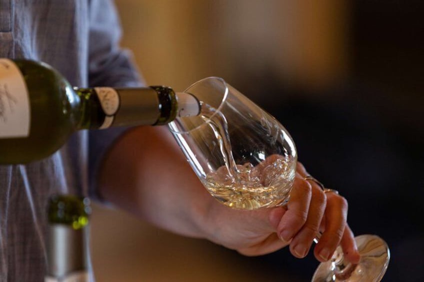 En person hælder vin i et glas. 5