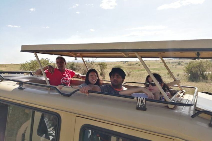 Four people in a safari vehicle with a clear view of the savannah landscape. 3