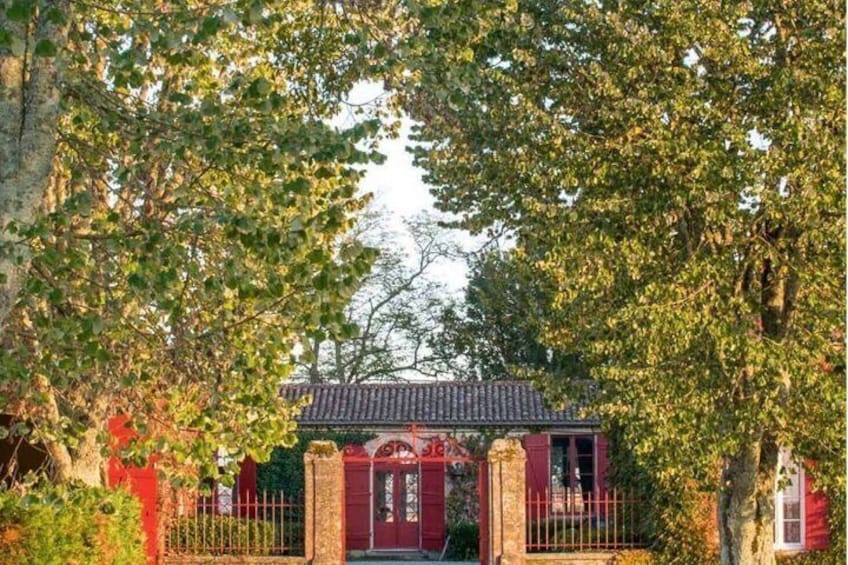 Une porte rouge surmontée d’un toit en tuiles, entourée d’arbres et de verdure. 5