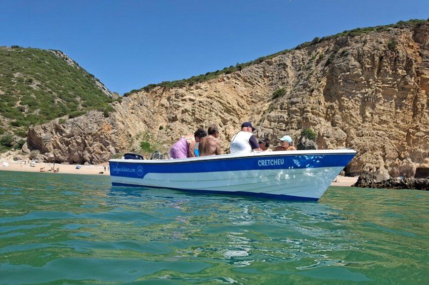 Een boot genaamd 'CRETCHOU' op kalm water, met een rotsachtige kustlijn en een heldere lucht. 3