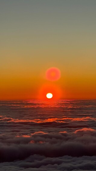 A sunset over the ocean with clouds below. 2