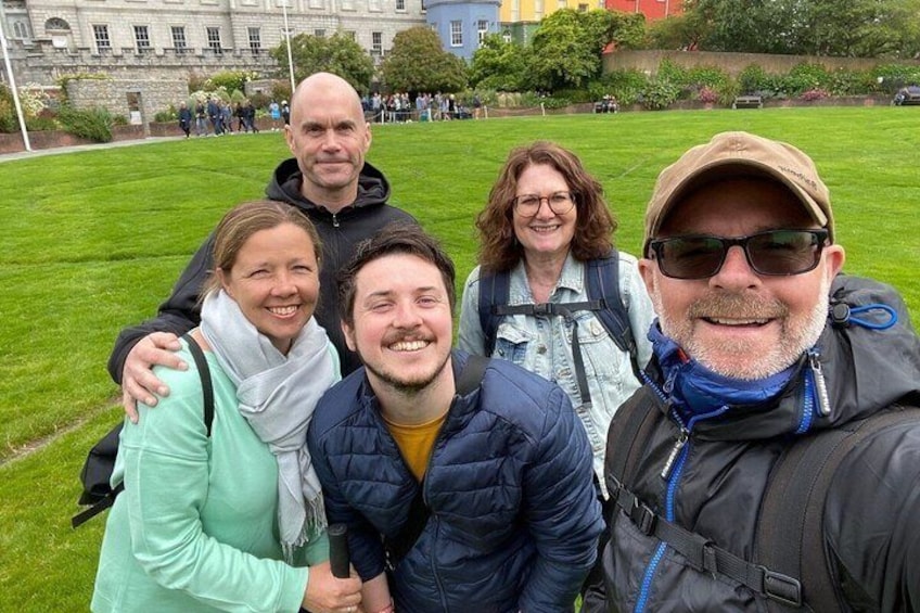 A group of people standing on a grassy field with a building in the background. 1