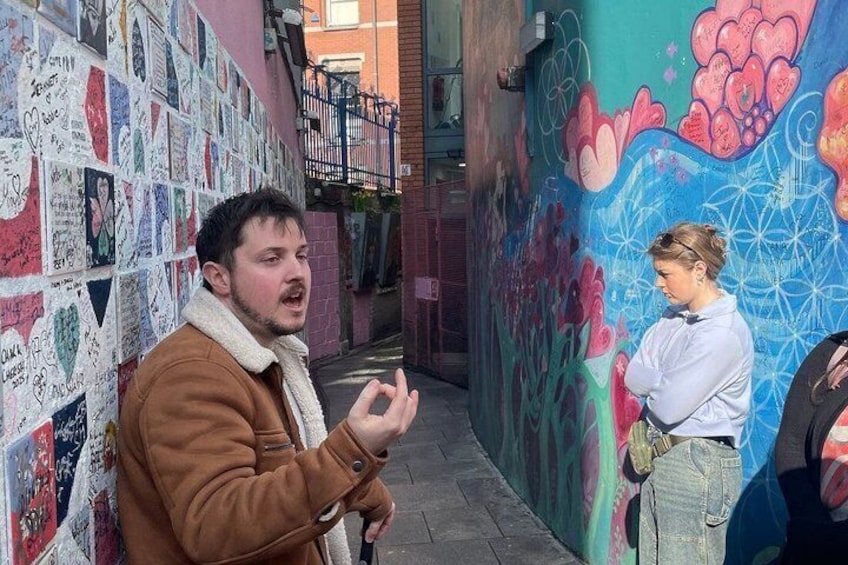 A man gesturing in an alley with graffiti-covered walls. 4