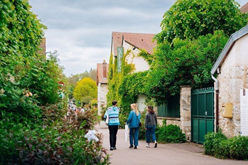 A narrow alley with stone buildings, lush greenery, and a green gate. 3